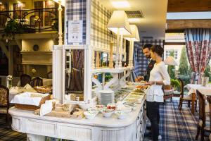 a woman standing in front of a buffet of food at Hotel St. Bruno in Giżycko