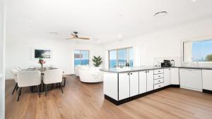 a kitchen and dining room with white cabinets and a table at The Family Entertainer - with sweeping water views in Salamander Bay