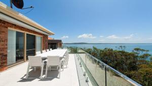 a balcony with a table and chairs and the ocean at The Family Entertainer - with sweeping water views in Salamander Bay