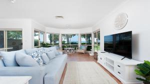 sala de estar con sofá azul y TV en Memories on the Beachfront, en Corlette