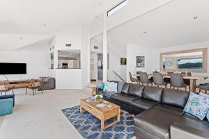 a living room with a couch and a table at Above and Beyond - Beautiful Home with Heated Pool and Views in Salamander Bay