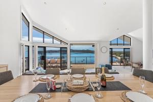 a dining room with a table and a view of the ocean at Above and Beyond - Beautiful Home with Heated Pool and Views in Salamander Bay