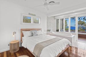 a white bedroom with a bed and a bath tub at Driftwood in Soldiers Point