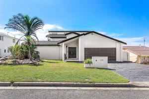 a white house with a palm tree in front of it at Above and Beyond - Beautiful Home with Heated Pool and Views in Salamander Bay