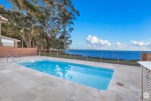 a swimming pool with a view of the ocean at Seaside Sanctuary - Waterfront Luxury Home with Heated Pool in Salamander Bay