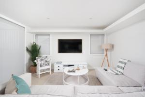 a white living room with a couch and a table at Baydream on the Beach - With Breathtaking Water Views in Corlette