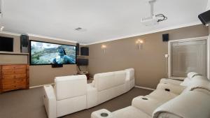 uma sala de estar com mobiliário branco e uma televisão de ecrã plano em Coast and Country Estate - 15m Heated Pool and Minutes to Beach em One Mile