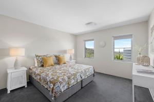 a white bedroom with a bed and a window at Grandview - Luxurious Entertainer with Spectacular Views in Nelson Bay