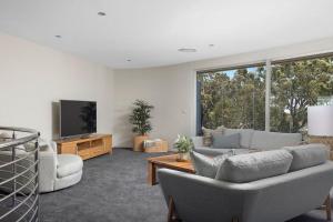 a living room with a couch and a tv at Grandview - Luxurious Entertainer with Spectacular Views in Nelson Bay