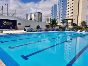 una gran piscina con agua azul y sillas azules en Flat Golden Dolphin Grand Hotel - Quarto e Sala Com Roupa de Cama e Banho - Piscinas 24h en Caldas Novas