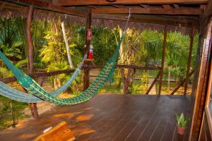 a hammock hanging from a wooden deck with trees at Tronco Tambopata Adventure in Puerto Maldonado