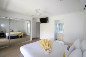 a white bedroom with a bed and a mirror at BLK Stays Guest House Deluxe Units Bellmere 