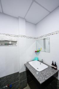 a white bathroom with a sink and a mirror at Thanh Ngoc Motel 2 in Buon Ma Thuot