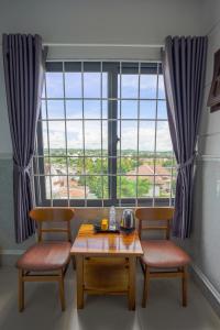 a table and two chairs in front of a large window at Thanh Ngoc Motel 2 in Buon Ma Thuot