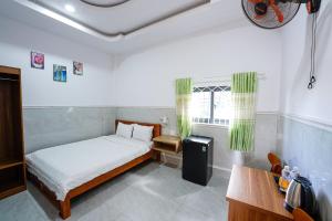 a bedroom with a bed and a desk and a window at Thanh Ngoc Motel 2 in Buon Ma Thuot