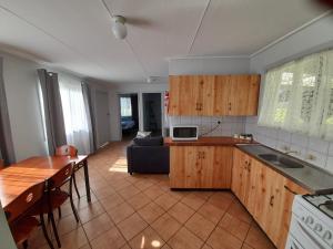 a kitchen with wooden cabinets and a living room at Kalgan River Chalets and Caravan Park in Kalgan