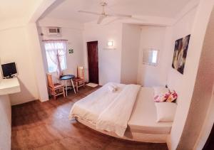 a bedroom with a white bed and a table at Sea Horse Guest House in Coron