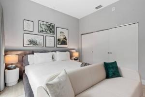 um quarto com uma cama branca e um sofá em Pretty Rola 303 Signature Apartment w King Bed Brand new and Central Location em Fort Lauderdale