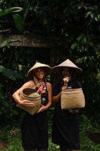 zwei Frauen mit Hüten, die nebeneinander stehen in der Unterkunft Bali Jungle Camping by Amerta Experience in Tabanan
