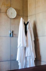 un reloj y tres camisas blancas colgando en una pared en Avela Lodge, en Hekpoort