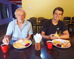 two men sitting at a table with plates of food at Hotel Rhinoceros-Homestay in Sauraha