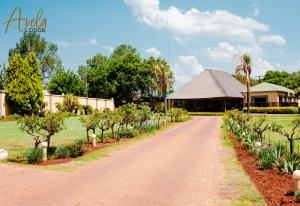 a path in a garden with a building and trees at Avela Lodge in Hekpoort