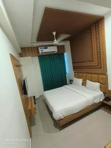 a bedroom with a bed and a green curtain at Hotel Asopalav in Gandhinagar