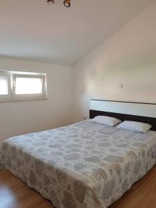 a white bedroom with a large bed with two pillows at Apartments by the sea Tkon, Pasman - 19017 in Tkon