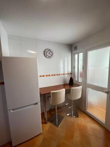 a kitchen with a table and chairs and a clock on the wall at Atico Infanta Eulalia in Sanlúcar de Barrameda