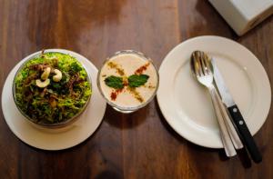 Hotel Tapas في كاتماندو: طاولة مع طبقين من الطعام ووعاء من السلطة
