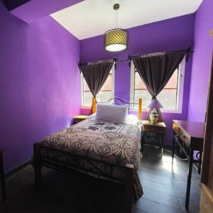 um quarto roxo com uma cama e um piano em Casa Jardín em Guanajuato