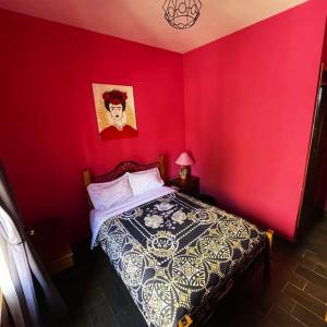 um quarto com uma cama com uma parede vermelha em Casa Jardín em Guanajuato