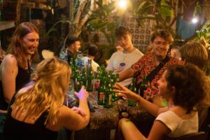 a group of people sitting around a table with bottles at Da Housetel Kuta in Kuta