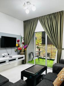 a living room with a couch and a tv and a balcony at SA @ Cameron Emerald Avenue in Brinchang