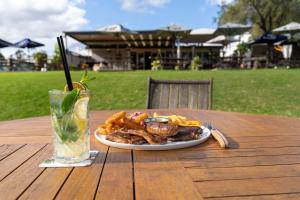 Ein Teller mit Essen und ein Getränk auf einem Holztisch in der Unterkunft The Coramba Hotel in Coramba