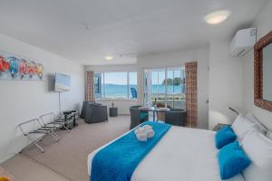a bedroom with a large bed and a living room at Waterfront Apartments Whitianga in Whitianga