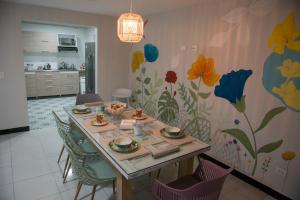 a dining room with a table and chairs with flowers on the wall at Casa Tangara Café y Hospedaje in Medellín