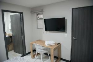 Habitación con mesa y TV en la pared. en Casa Tangara Café y Hospedaje, en Medellín