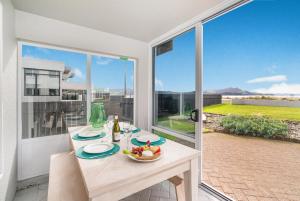 a table with a bowl of fruit on it in front of a window at Waterfront Apartments Whitianga in Whitianga