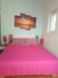 a pink bed in a white room with two lamps at Apartments by the sea Brist, Makarska - 19330 in Podaca