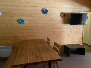 a dining room with a wooden table and a tv at Appartement en centre ville à 30m du télécabine in Font-Romeu-Odeillo-Via