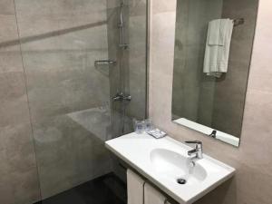 La salle de bains est pourvue d'un lavabo et d'une douche avec un miroir. dans l'établissement Hotel Ciudad de Fuenlabrada, à Fuenlabrada