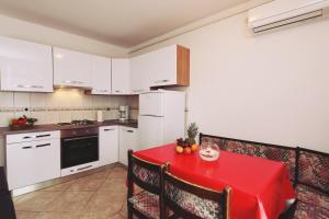 a kitchen with a table with a red table cloth at Apartments by the sea Malinska, Krk - 19264 in Malinska