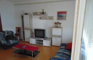 Apartments by the sea Seget Donji, Trogir - 19351 في تروغير: غرفة معيشة مع أريكة وتلفزيون
