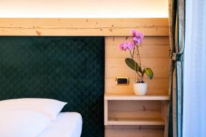 um quarto com uma cama e uma planta numa prateleira em Garni Hotel and Apartments Wildbach em Selva di Val Gardena