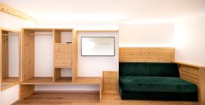 a room with a green couch and wooden shelves at Garni Hotel and Apartments Wildbach in Selva di Val Gardena