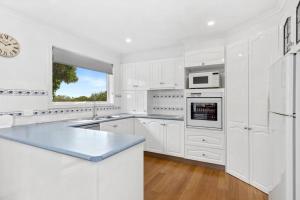 a white kitchen with white appliances and a window at OASIS ON SUNSET - tranquility close to the ocean in Ocean Grove