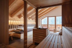 a bedroom in a wooden house with a large window at Berghotel Sanví in San Martino in Badia
