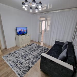 a living room with a black couch and a tv at Квартира у моря in Aktau
