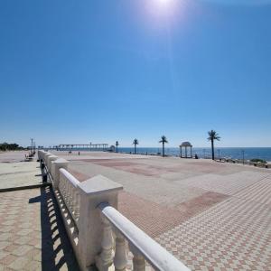 a walkway to the beach with a pier in the background at Квартира у моря in Aktau